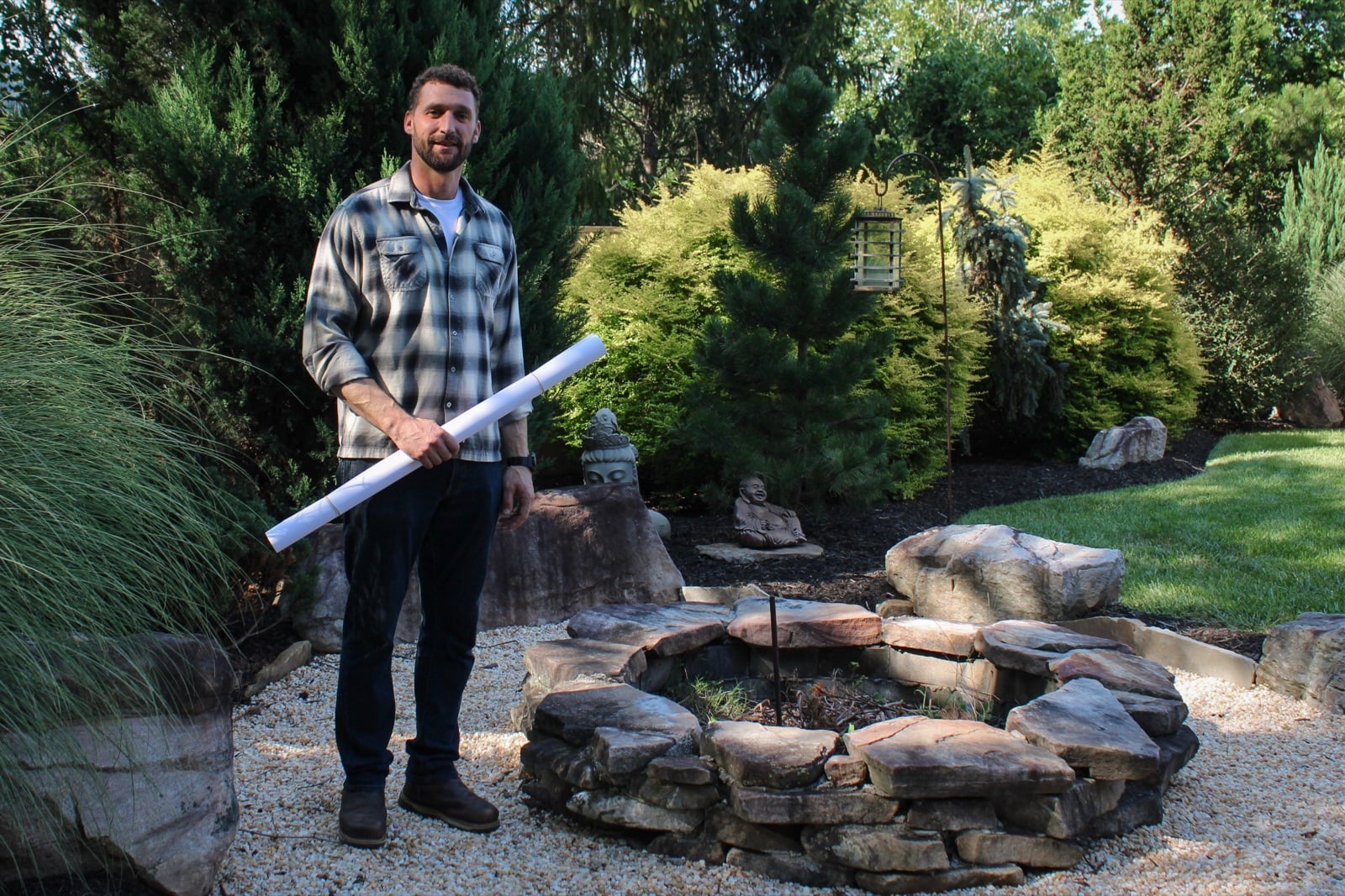 Jon Lloyd, owner of Smith and Lloyd Landscaping and Design, holding a rolled landscape plan in a finished garden